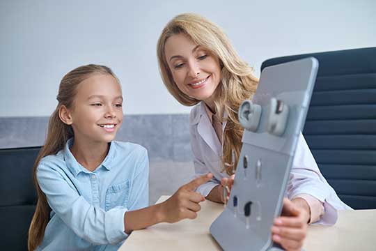 Mother and daughter looking at different types of hearing aids.