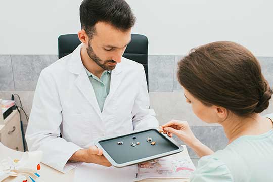 Man and woman looking at hearing aids that need to be repaired. 